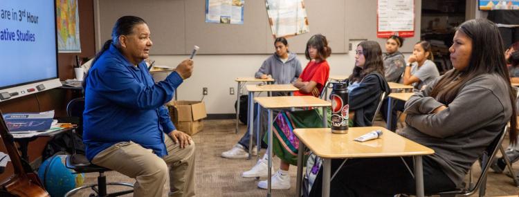 A teacher speaks to a classroom full of students, fostering an interactive learning environment.