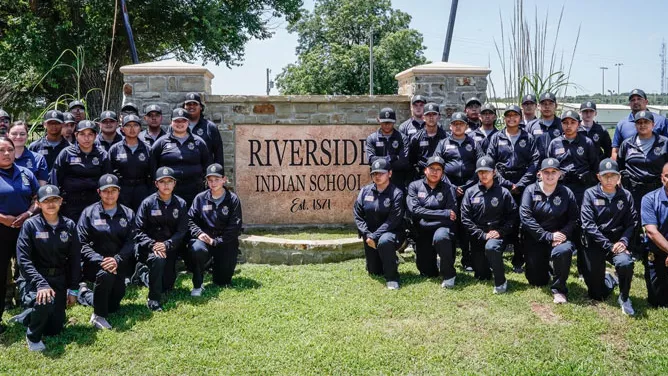 The Youth Indian Police Academy provides cadets posing in front of the Riverside school sign. 
