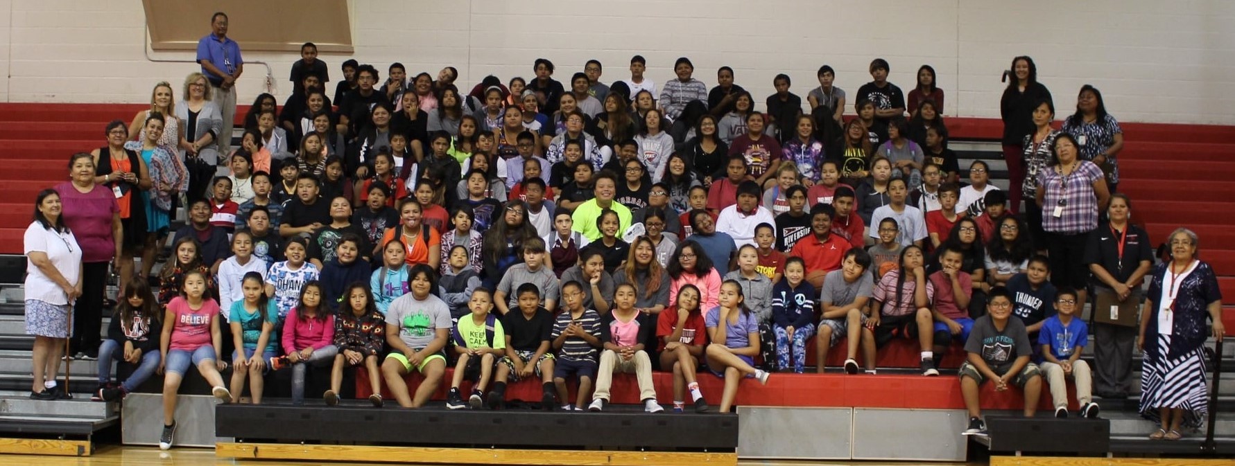 Students and staff posing on the bleachers in the gym.