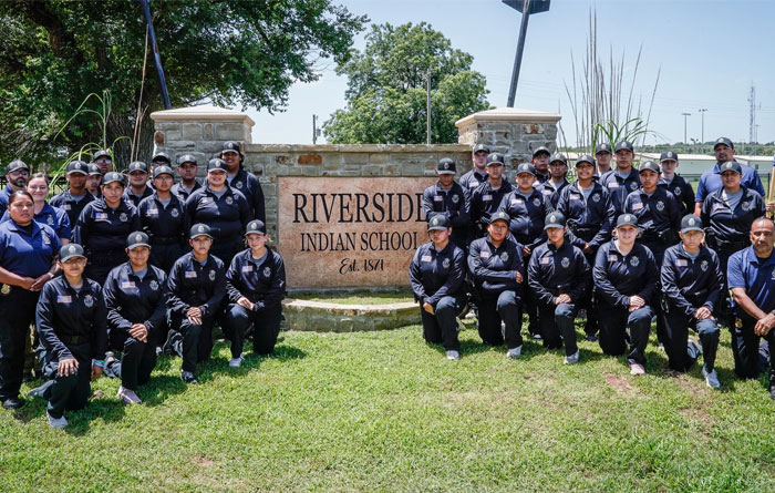The Youth Indian Police Academy provides cadets posing in front of the Riverside school sign. 