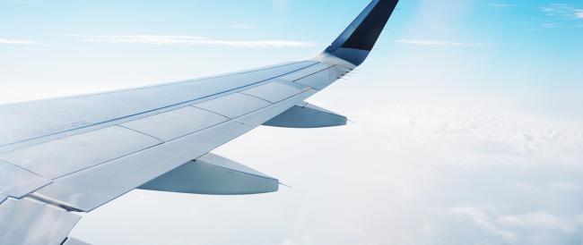 view of airplane wing and clouds from window of airplane in flight